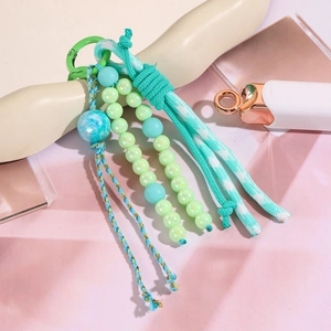 Vue détaillée du porte-clés artisanal perlé avec pompon vert et breloque d'amour