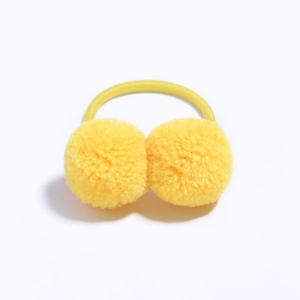 Close-up of bright yellow double fluffy pompom hair ties on a plain white background