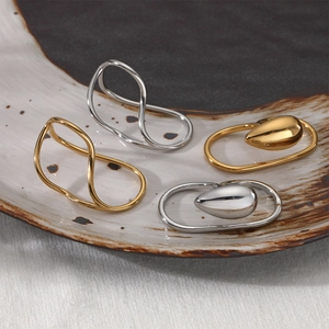 Minimalist 316 stainless steel irregular wavy rings in gold and silver finish on ceramic