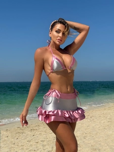 Detail of glossy metallic pink and silver bikini set with ruffled mini skirt on beach