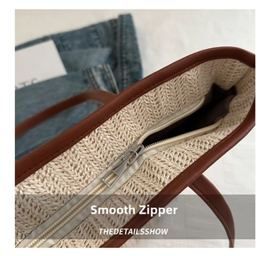 Detail of cream straw tote bag showing brown leather trim and smooth silver metal zipper