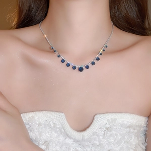Detail of silver clavicle chain featuring multiple blue round zircon pendant stones