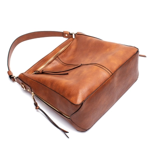 Detail view of brown faux leather tote bag with fringe accents and gold hardware zipper