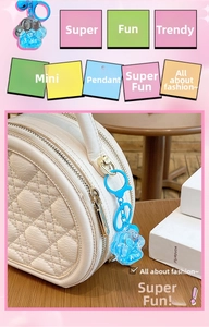 Detailed view of a blue resin cat paw quicksand keychain attached to a white quilted bag