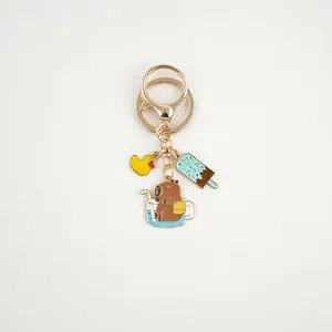 Detailed view of Capybara enamel keychain with duck and popsicle charms on gold hook