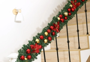 Close-up of 2.7m green Christmas garland with red flowers on wooden stairs