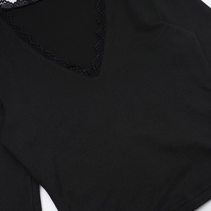 Close-up of the delicate black lace trim on the V-neckline of a soft knitted sweater