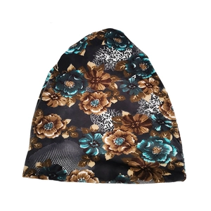 Close-up of knit slouchy beanie featuring teal floral and grey animal print patterns