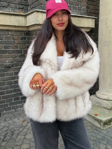 Close-up of fluffy faux fox fur texture on a cream winter coat with wide lapels