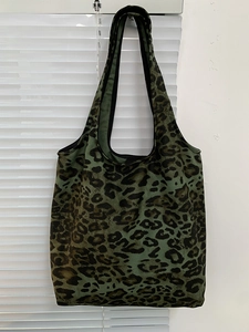 Dettaglio ravvicinato della borsa in tela leopardata verde scuro con bordo nero