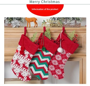 Three knit Christmas stockings with reindeer and snowflake patterns hanging on a fireplace