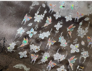 Close-up of 3D iridescent butterfly and floral nail stickers with pearl details