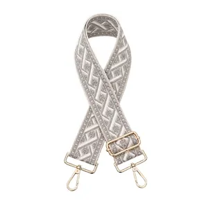 Close-up of grey and white woven jacquard bag strap with adjustable gold metal buckle