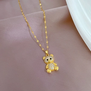 Detail of a gold bear pendant necklace with sparkling white and green crystals on satin