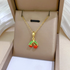 Détail du collier pendentif cerise en émail rouge et feuilles vertes dans son écrin à bijoux