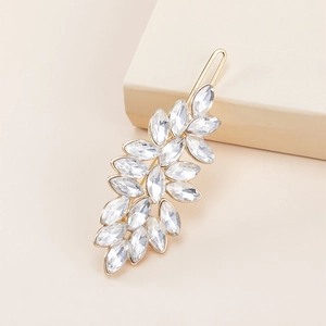 Elegant gold metal leaf hair clip with sparkling crystals on a cream-colored box