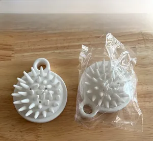 Close-up of a white silicone scalp massage brush with soft conical bristles and hanging loop