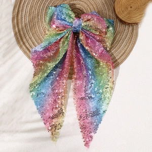 Sparkly rainbow sequin oversized bow hair clip with streamers on a straw hat background