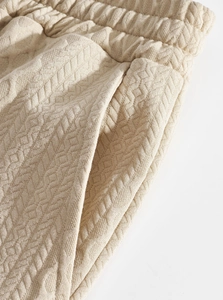 Detailed texture of knit joggers with elastic waistband and pocket in beige