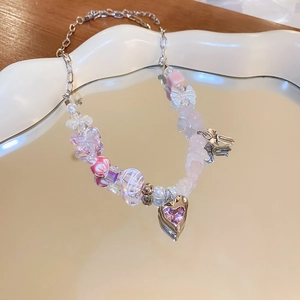 Detail of sweet beaded necklace featuring pink heart zircon pendant and metal bow charm