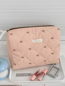Pink quilted cosmetic bag with brown bow embroidery and secure zipper closure