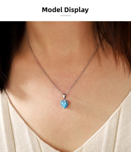 Primo piano di una collana a cuore in argento con gemma blu sul collo di donna