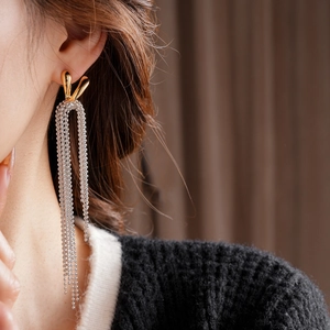 Close-up of elegant long tassel earrings with gold irregular arc and silver bead chains