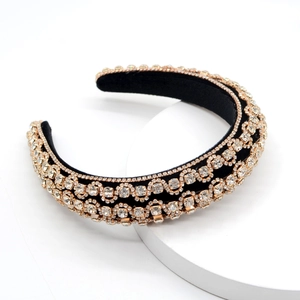 Detailed macro view of black velvet headband with gold hollowed-out rhinestone patterns