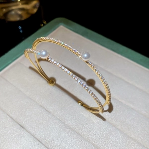 Detail of double-layer gold open bangle featuring pearls and sparkling zircon accents