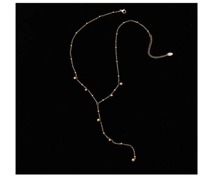Close-up of golden beaded Y-necklace with long tassel pendant on a black background
