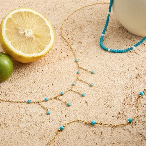 Collier en acier titane doré avec perles bleues sur pierre décoré de citrons frais
