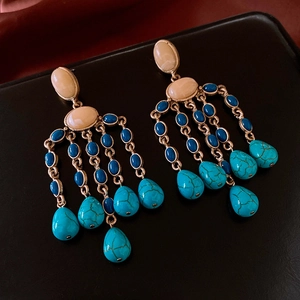 Detailed shot of vintage gold drop earrings with turquoise stones on black leather