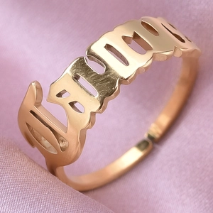 Detailed macro view of custom gold-plated stainless steel name ring on silk background