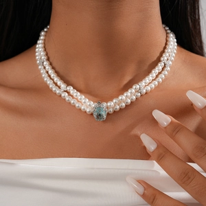 Close-up of double-layered pearl necklace with a central blue gemstone star pendant