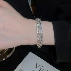 Luxe three-layer silver bangle with sparkling round zircons worn against a black sleeve