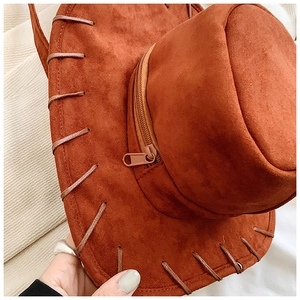 Close-up of brown suede cowboy hat backpack showing zipper pocket and rope detail