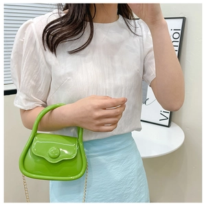 Detail view of mini bright green patent leather crossbody bag with elegant gold chain strap