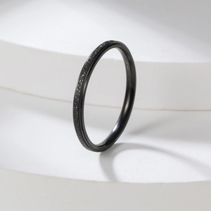 Macro shot of minimalist 2mm black ring featuring frosted texture and polished inner surface