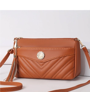 Detailed view of brown PU leather women crossbody bag with quilted chevron and tassel accent.