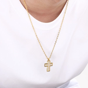 Close-up of gold-plated stainless steel cross necklace with inset zirconias on a person