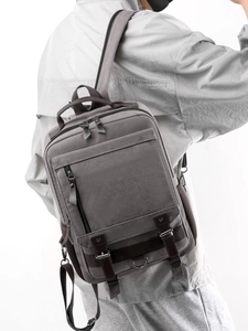 Vintage canvas and leather backpack in dark grey and brown, worn by a male model