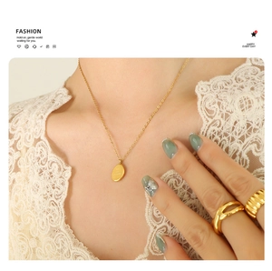 Detail of 18K gold plated oval pendant necklace on model with white lace clothing