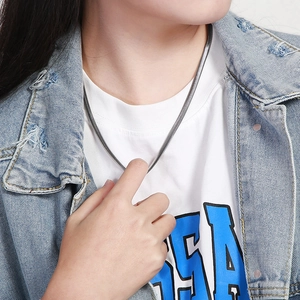 Close-up of minimalist silver flat snake chain necklace worn on model with denim jacket