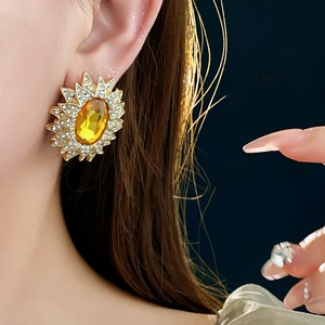 Detailed view of vintage gold sunflower earrings with yellow gems on model ear