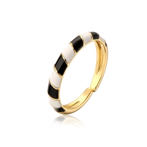 Macro shot of geometric gold-plated ring with black and white enamel drip details
