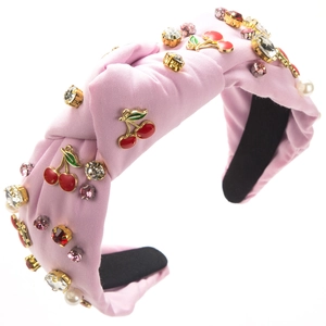 Detail eines rosa Stoffstirnbandes mit glitzernden Strasssteinen und Kirsch-Anhänger