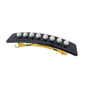 Detail of elegant black acetate hair clip featuring eight gray pearls and golden clasp