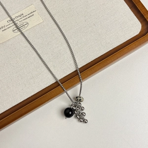 Détail du collier chaîne argenté avec perle noire et pierre dalmate sur plateau bois