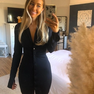 Detail of slim fit black shirt dress showing long sleeves and single-breasted button closure