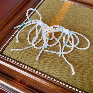 Close-up of handmade bow jewelry with pastel beads and pearls on green background